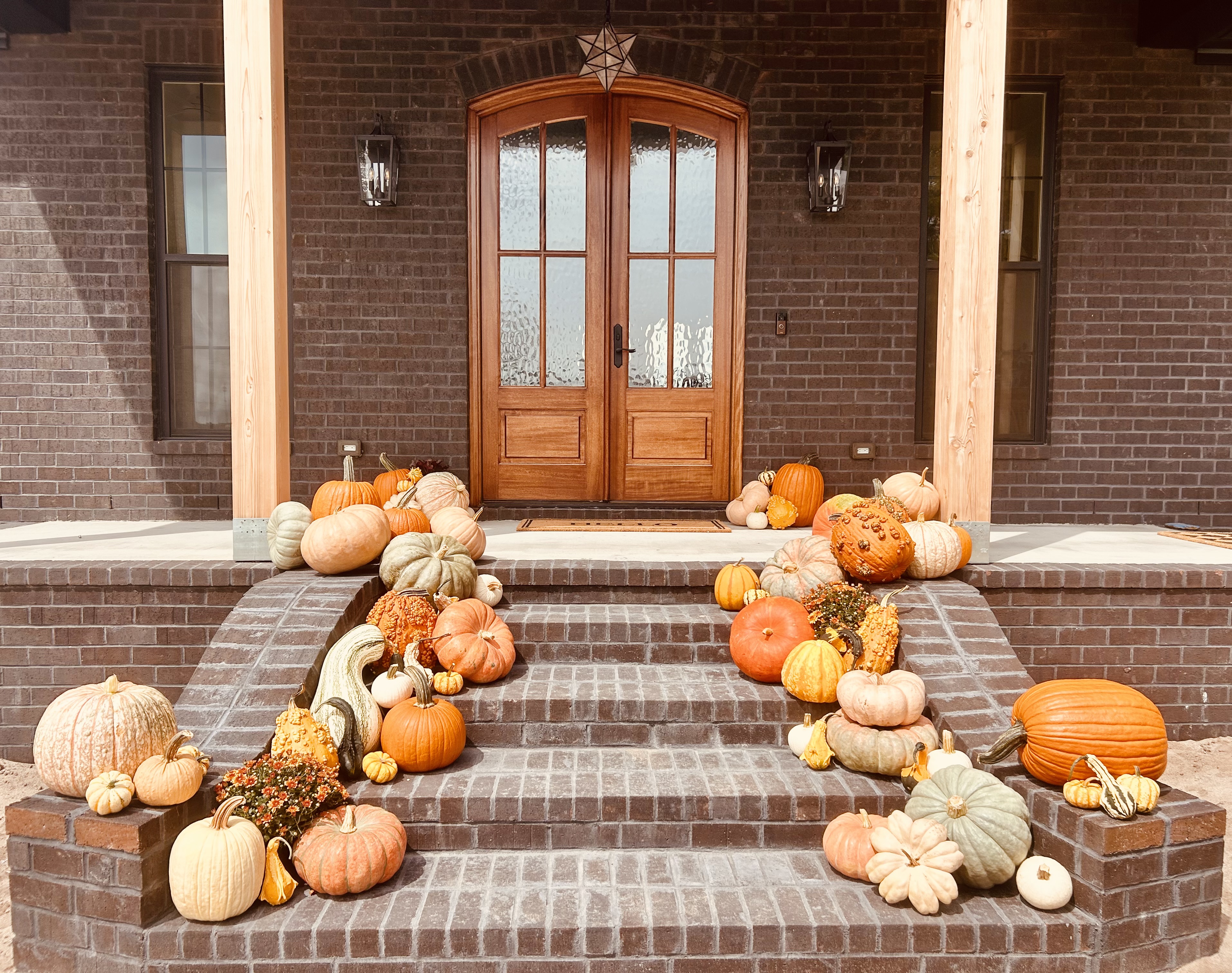 Large pumpkin and gourd display arranged along wide brick entry steps